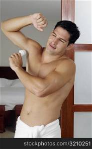Young man applying deodorant under his armpit