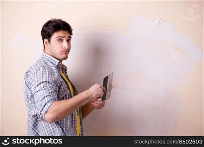 Young man applying plaster on wall at home