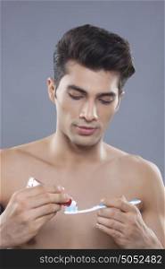 Young man applying toothpaste on toothbrush