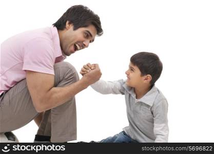 Young man arm wrestling with his son over white background