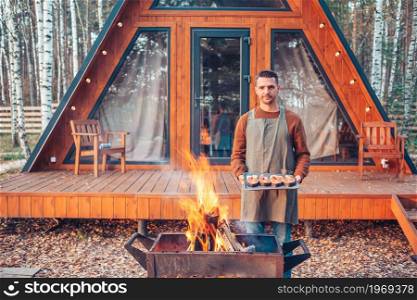 Young man at autumn warm day grill outdoors. Happy man in autumn grilled