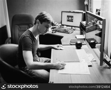 Young man at home using a computer, freelance developer and designer working at home, black and white photo