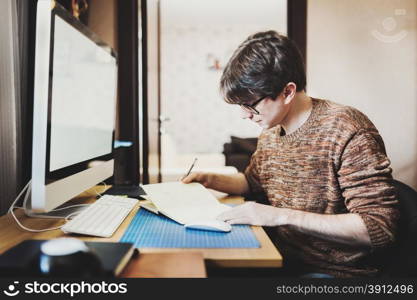 Young man at home using a computer, freelance developer or designer working at home