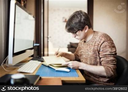 Young man at home using a computer, freelance developer or designer working at home.