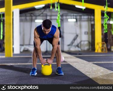 young man athlete exercise with fitness kettlebell at crossfitness gym. man exercise with fitness kettlebell