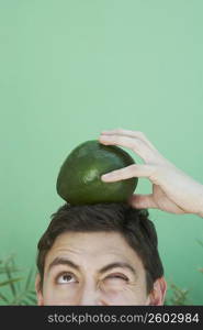 Young man balancing an avocado on his head