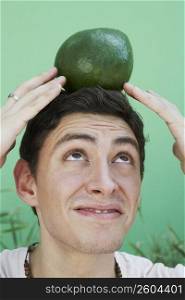 Young man balancing an avocado on his head