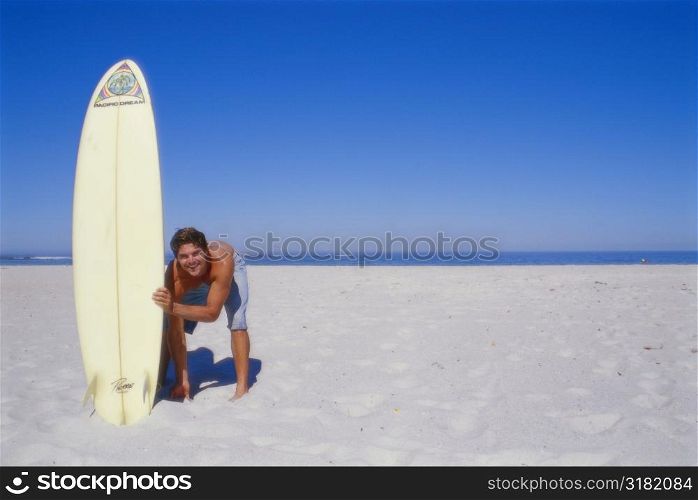Young man bending and holding a surfboard