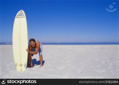 Young man bending and holding a surfboard