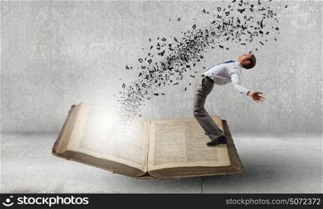 Young man benting to evade characters flying from book. Magic of reading