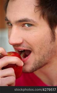 Young man biting into red apple