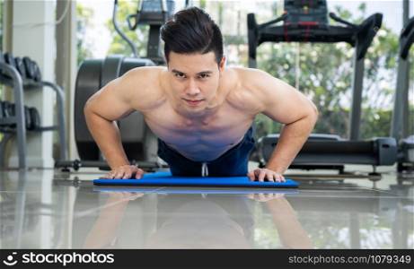 Young man bodybuilder doing push up in fitness center. Healthy lifestyle and body building concept.
