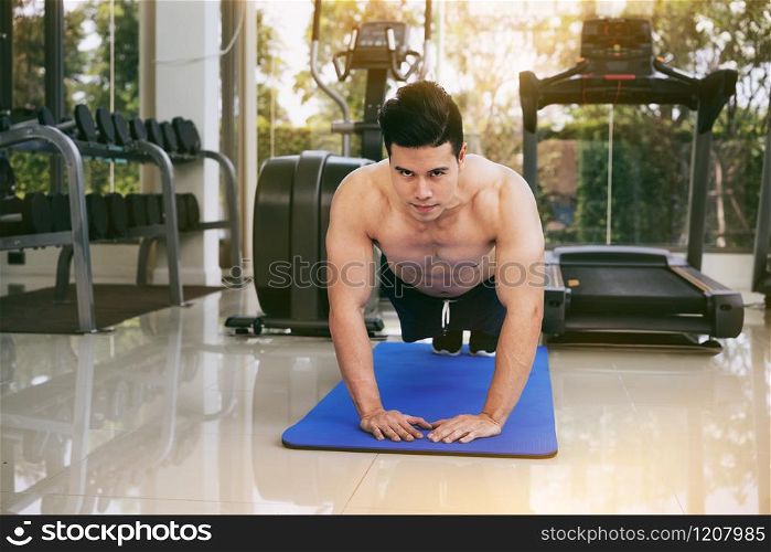 Young man bodybuilder doing push up in fitness center. Healthy lifestyle and body building concept.