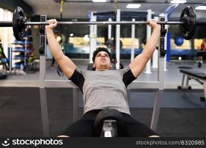 Young man bodybuilder doing weight lifting in gym. Attractive man wearing sportswear