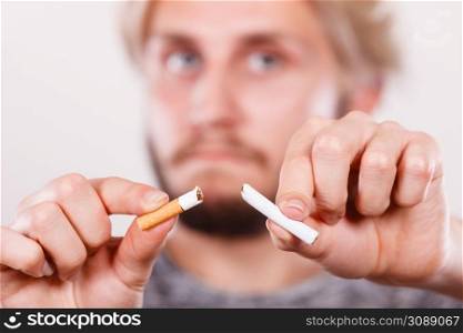 Young man breake down cigarette. Winning with addicted nicotine problems, stop smoking. Quitting from addiction concept.. Young man is breaking a cigarette