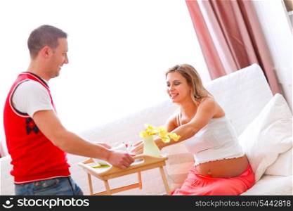 Young man bring breakfast to his happy pregnant wife&#xA;