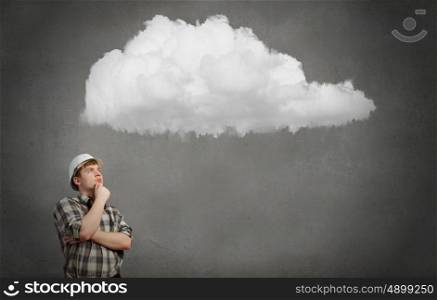 Young man builder looking thoughtfully at cloud in sky. Idea concept. Builder has an idea