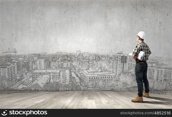 Young man builder looking thoughtfully at construction project. Idea concept. Builder has an idea