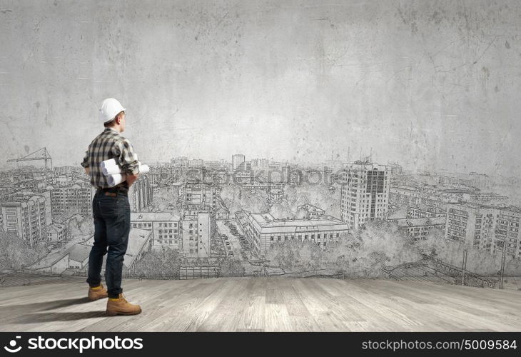 Young man builder looking thoughtfully at construction project. Idea concept. Builder has an idea