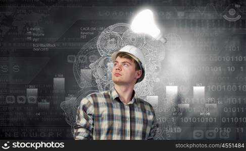 Young man builder looking thoughtfully at light bulb. Idea concept. Builder has an idea