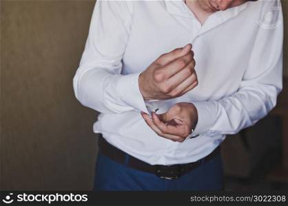 Young man buttoning shirt sleeve.. Man buttons sleeve white shirt 304.
