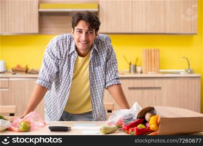 Young man calculating expences for vegetables in kitchen 