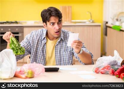 Young man calculating expences for vegetables in kitchen . The young man calculating expences for vegetables in kitchen 