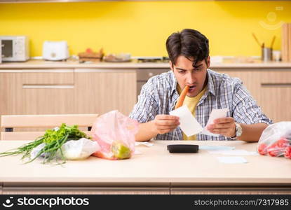 Young man calculating expences for vegetables in kitchen 