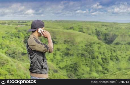 Young man calling by cell phone, young man in field calling by cell phone, young man calling by phone from back with copy space
