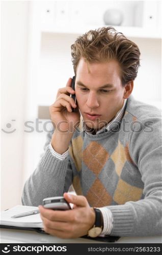 Young man calling on mobile phone at home.