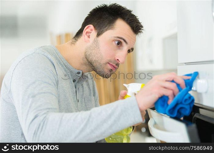 young man carefully cleaning oven