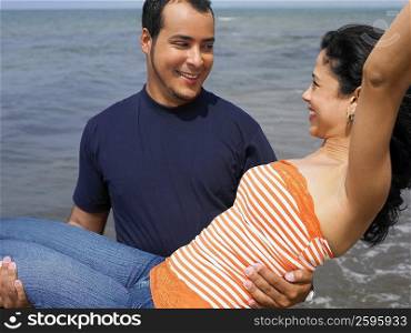 Young man carrying a young woman and smiling