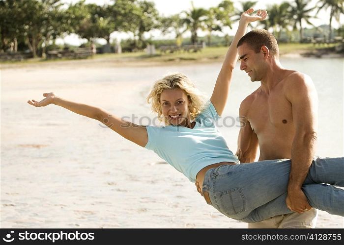 Young man carrying a young woman on the beach