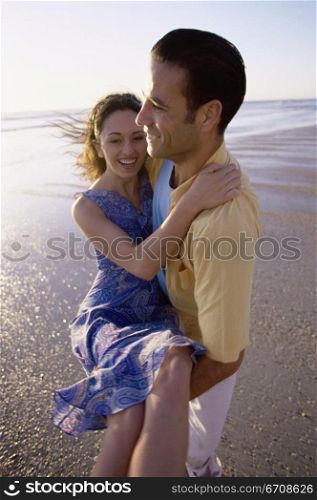 Young man carrying a young woman on the beach