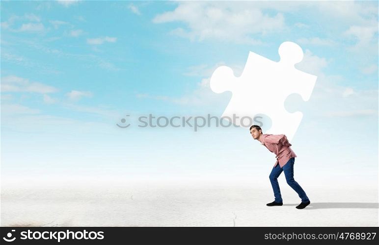 Young man carrying element of jigsaw on his back. Man carry puzzle