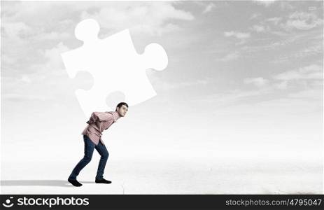 Young man carrying element of jigsaw on his back. Man carry puzzle