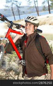 Young Man Carrying Mountain Bike in field