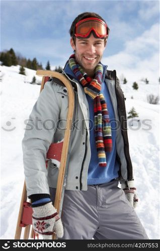 Young Man Carrying Sled In Alpine Landscape