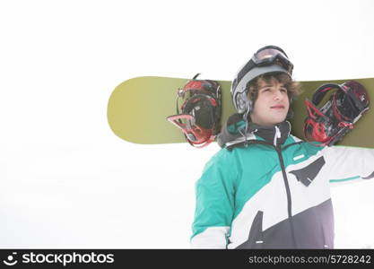 young man carrying snowboard against clear sky