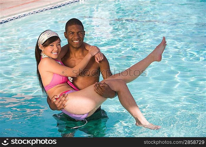 Young Man Carrying Young Woman in Swimming Pool, Portrait