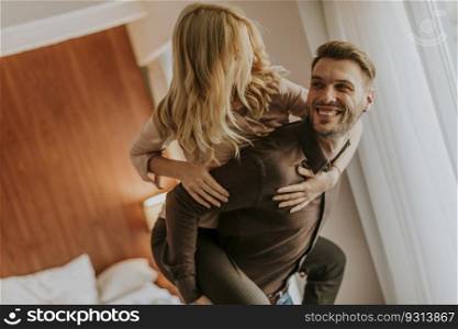 Young man carrying young woman on his back and having fun