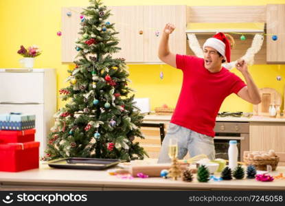 Young man celebrating Christmas in kitchen . The young man celebrating christmas in kitchen 