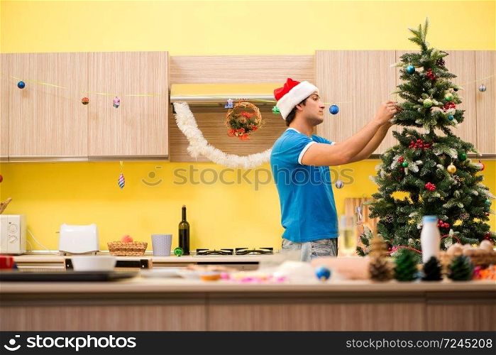 Young man celebrating Christmas in kitchen . The young man celebrating christmas in kitchen 