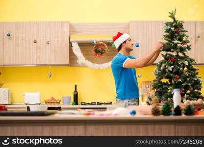 Young man celebrating Christmas in kitchen . The young man celebrating christmas in kitchen 