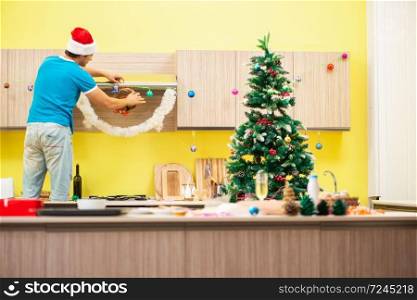Young man celebrating Christmas in kitchen . The young man celebrating christmas in kitchen 