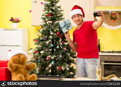 Young man celebrating Christmas in kitchen . The young man celebrating christmas in kitchen 