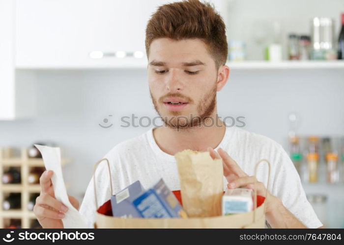 young man checking his shopping against a list