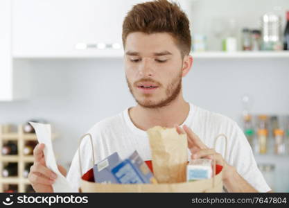 young man checking his shopping against a list