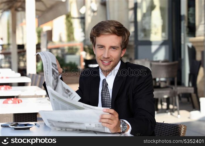Young man cheerful reading newspaper