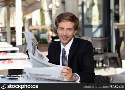 Young man cheerful reading newspaper